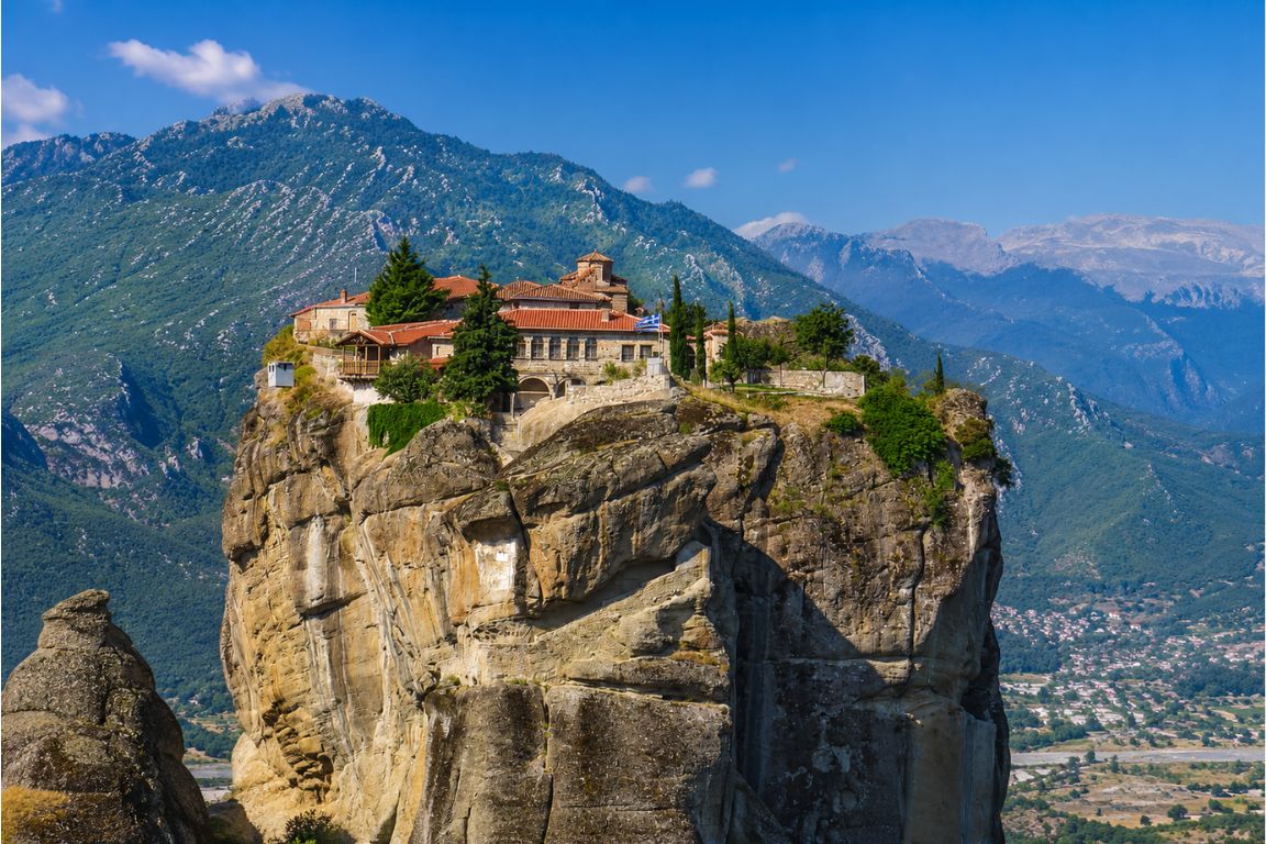 Panoramic view of the Holy Trinity Monastery standing on a dramatic rock formation surrounded by the Meteora mountains during a Meteora Tours excursion